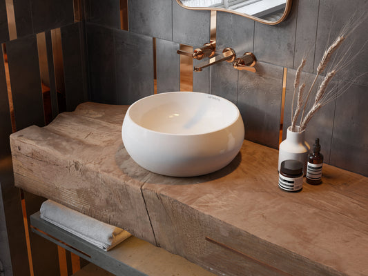 Ronde keramische waskom witte kleur op houten badmeubel met bronze inbouwkraan