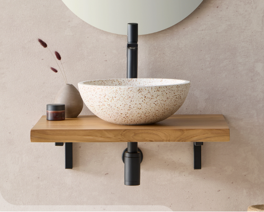 Beige terrazzo waskom op houten badmeubel met zwarte kraan en spiegel