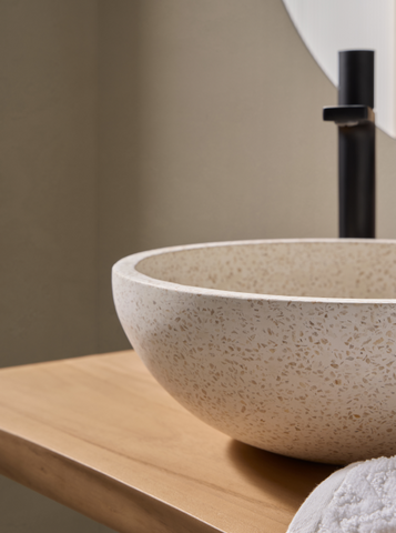 Terrazzo waskom 35x35x12cm in witte, beige tint op licht houten blad met zwarte opbouwkraan en zachte handdoeken voor een serene uitstraling