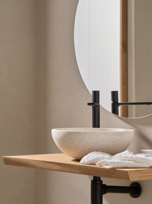 Terrazzo waskom 35x35x12cm in witte, beige tint op licht houten blad met zwarte opbouwkraan en zachte handdoeken voor een serene uitstraling