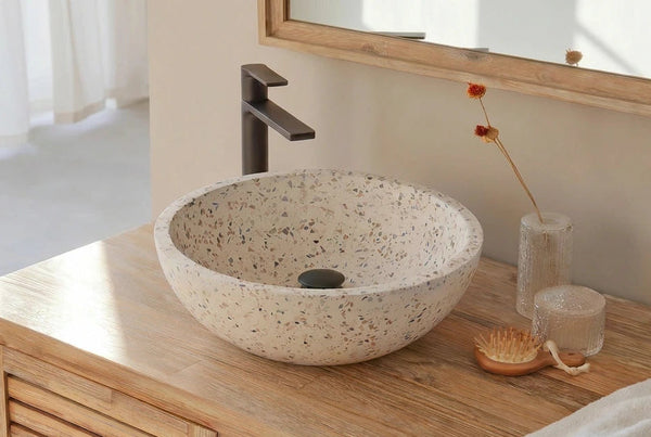 Terrazzo waskom met spikkels op houten meubel voor het raam