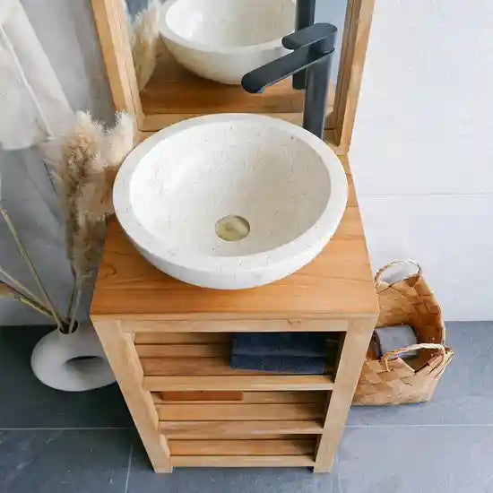 een beige natuurstenen waskom op een houten meubel met een zwarte kraan. 