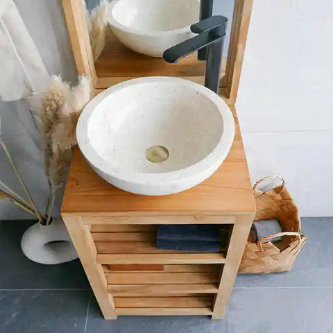 een beige natuurstenen waskom op een houten meubel met een zwarte kraan. 