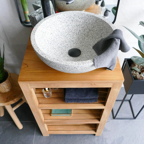 Ronde wit gespikkelde natuursteen waskom terrazzo op houten meubel met accessoires en decoratie in moderne badkamer
