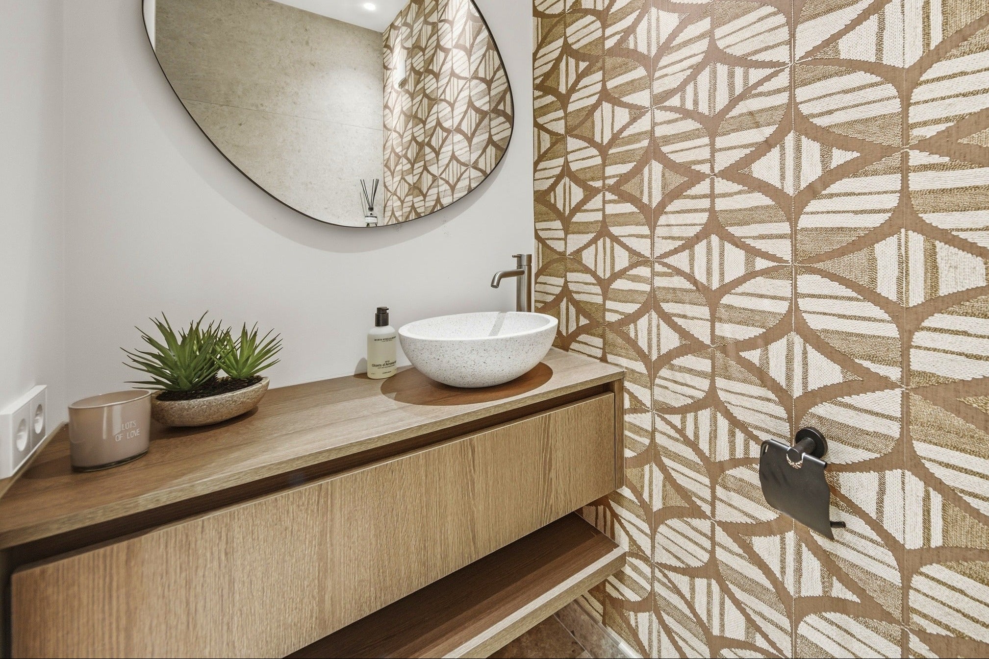 Witte terrazzo waskom Venecia op een eiken zwevend badmeubel in een toilet met gedessineerde wandtegels