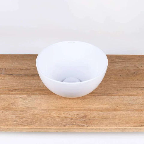 Ronde witte keramische waskom 28x28x14cm op houten blad in neutrale badkamer setting, ideaal als opbouwmodel voor moderne interieurs
