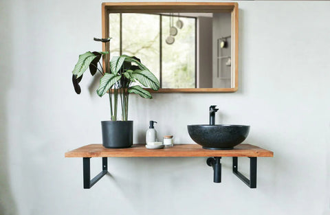 Zwarte natuurstenen ronde waskom op houten plank met zwarte opbouwkraan in moderne badkamer